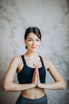 A young woman in a peaceful yoga pose indoors, embodying mindfulness and wellness.