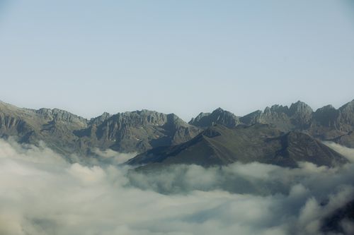 Free Stunning mountain peaks rise above a valley filled with clouds under a clear sky. Stock Photo