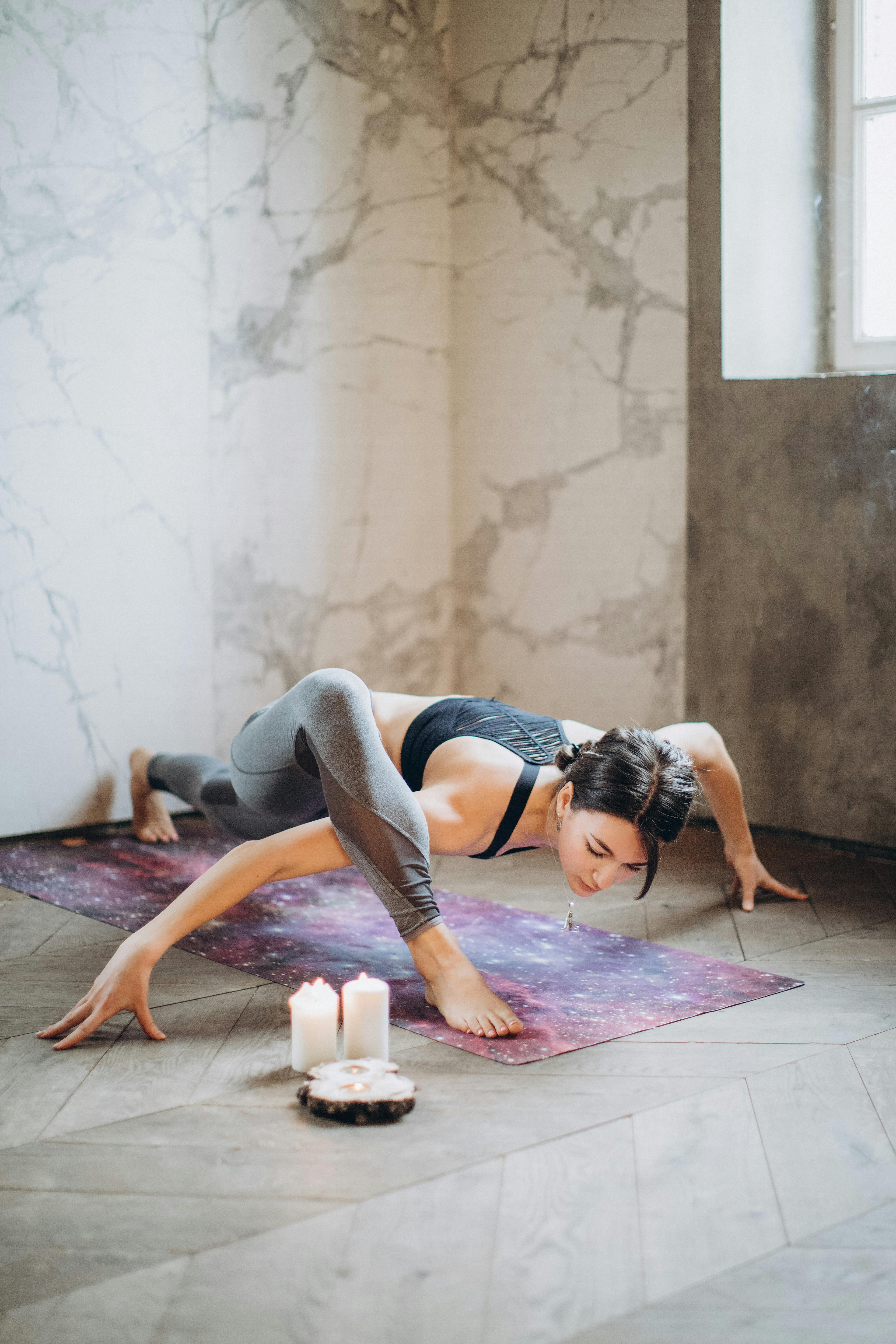 Woman practicing yoga on a purple mat by candlelight