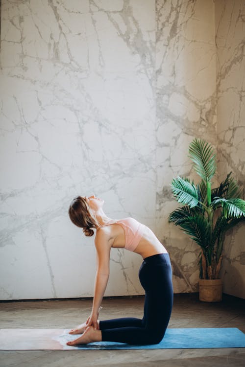 Woman in Pink Tank Top and Blue Leggings Bending Her Body