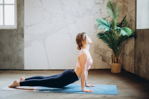 Mulher Com Sutiã Esportivo Rosa E Legging Preta Fazendo Ioga Em Um Tapete De Ioga