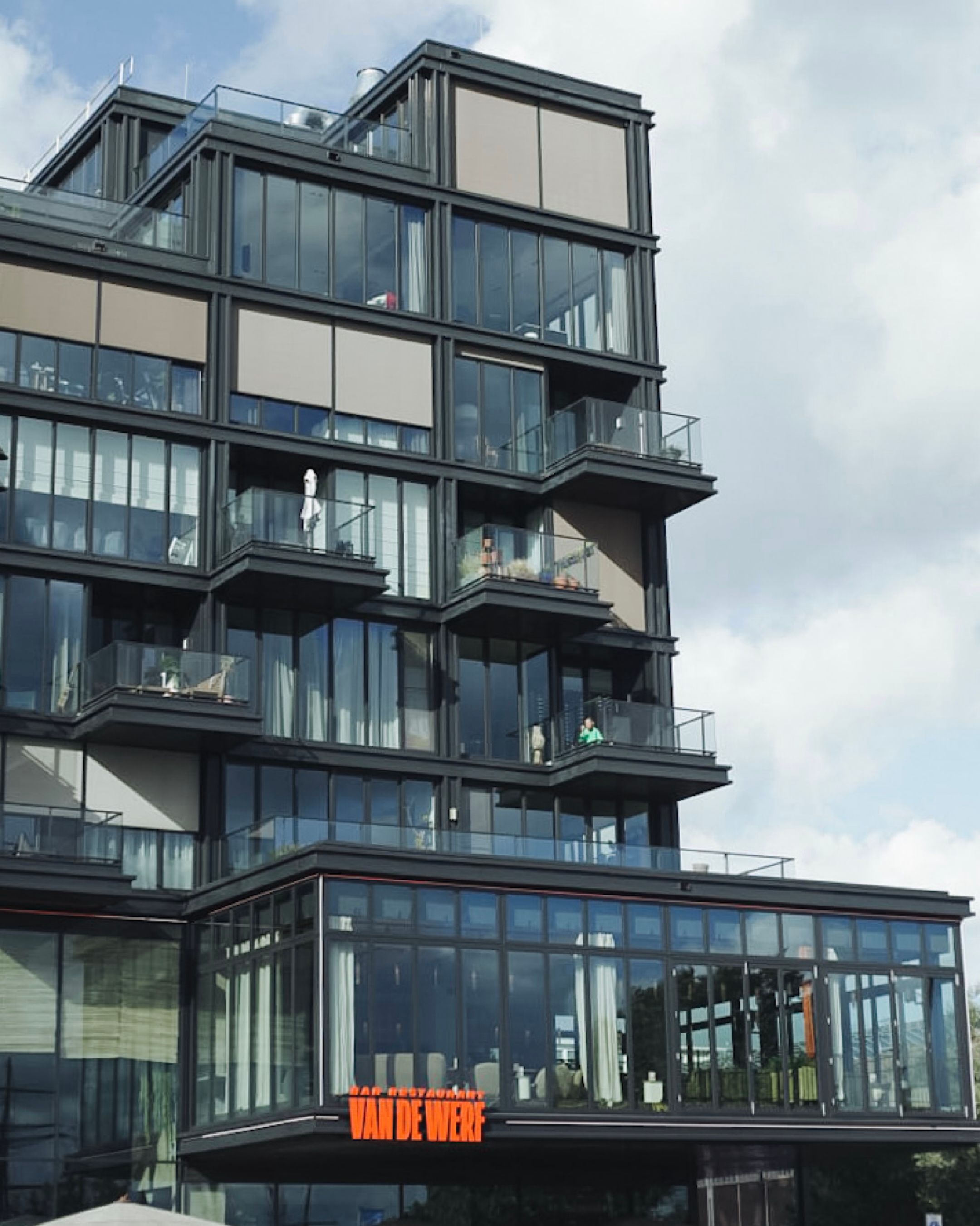 Modern urban apartment building with glass facade and balconies.