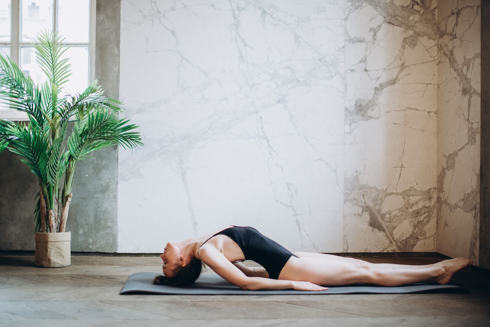 Person practicing a backbend yoga pose on a mat during a home yoga session