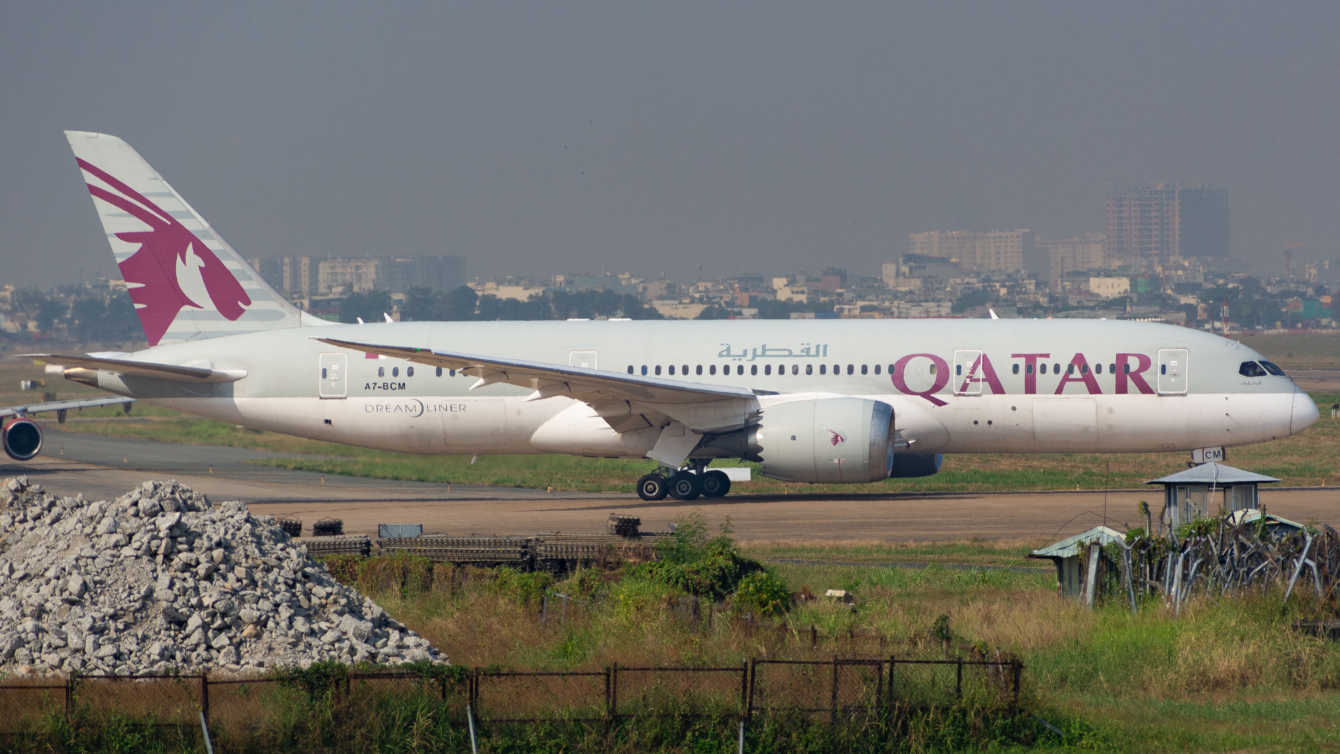 Qatar Airways Boeing 787 Dreamliner on a runway, ready for takeoff at an airport.