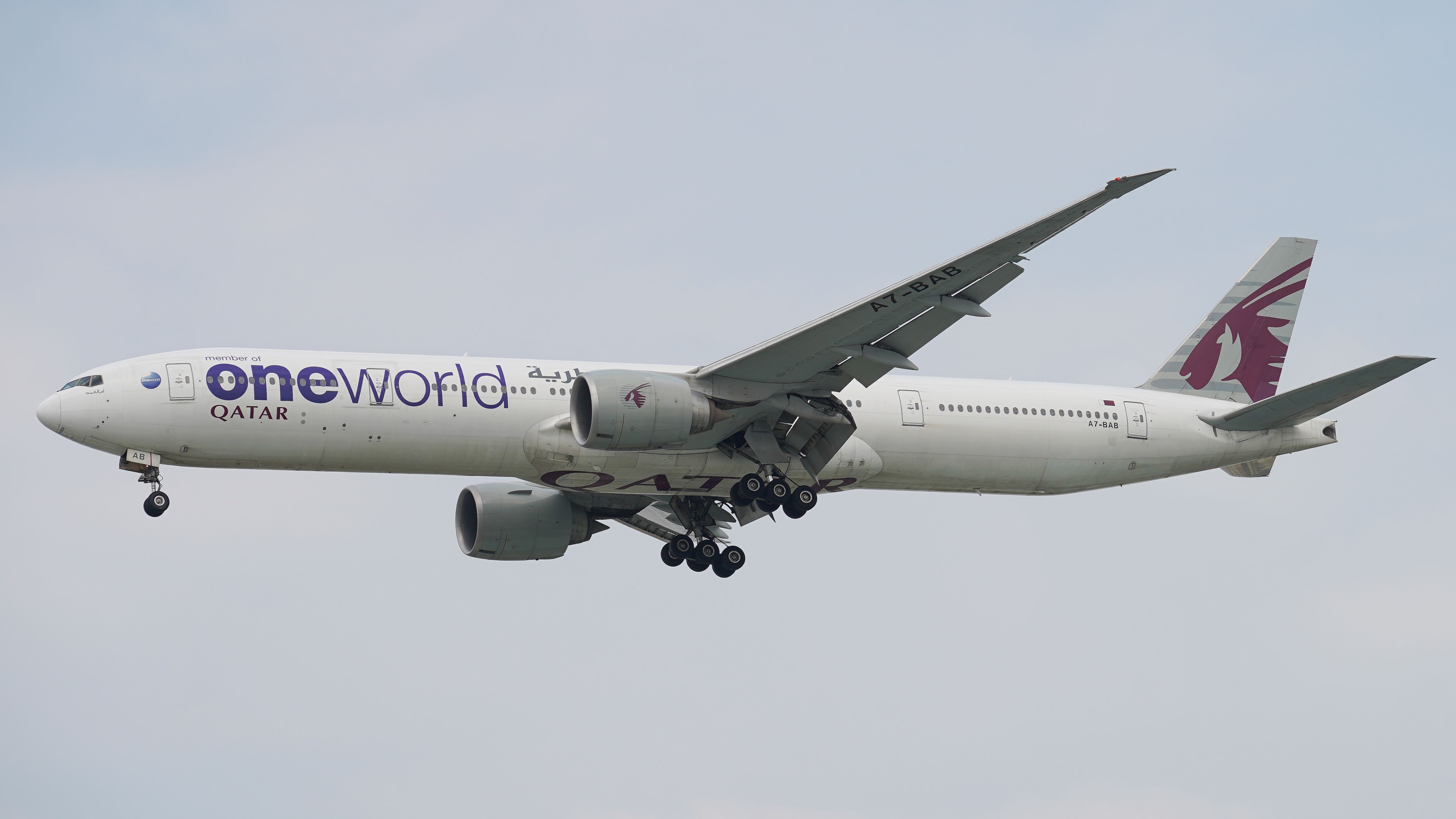 Aeronave Boeing 777 da Qatar Airways com a pintura da Oneworld em pleno voo.