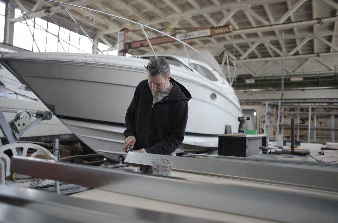 Mécanicien Barbu Travaillant Avec Une Partie Métallique Près Du Bateau