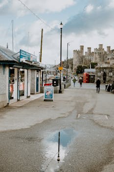 Charming view of Conwy Castle and street with water reflection and people, capturing the essence of Wales.