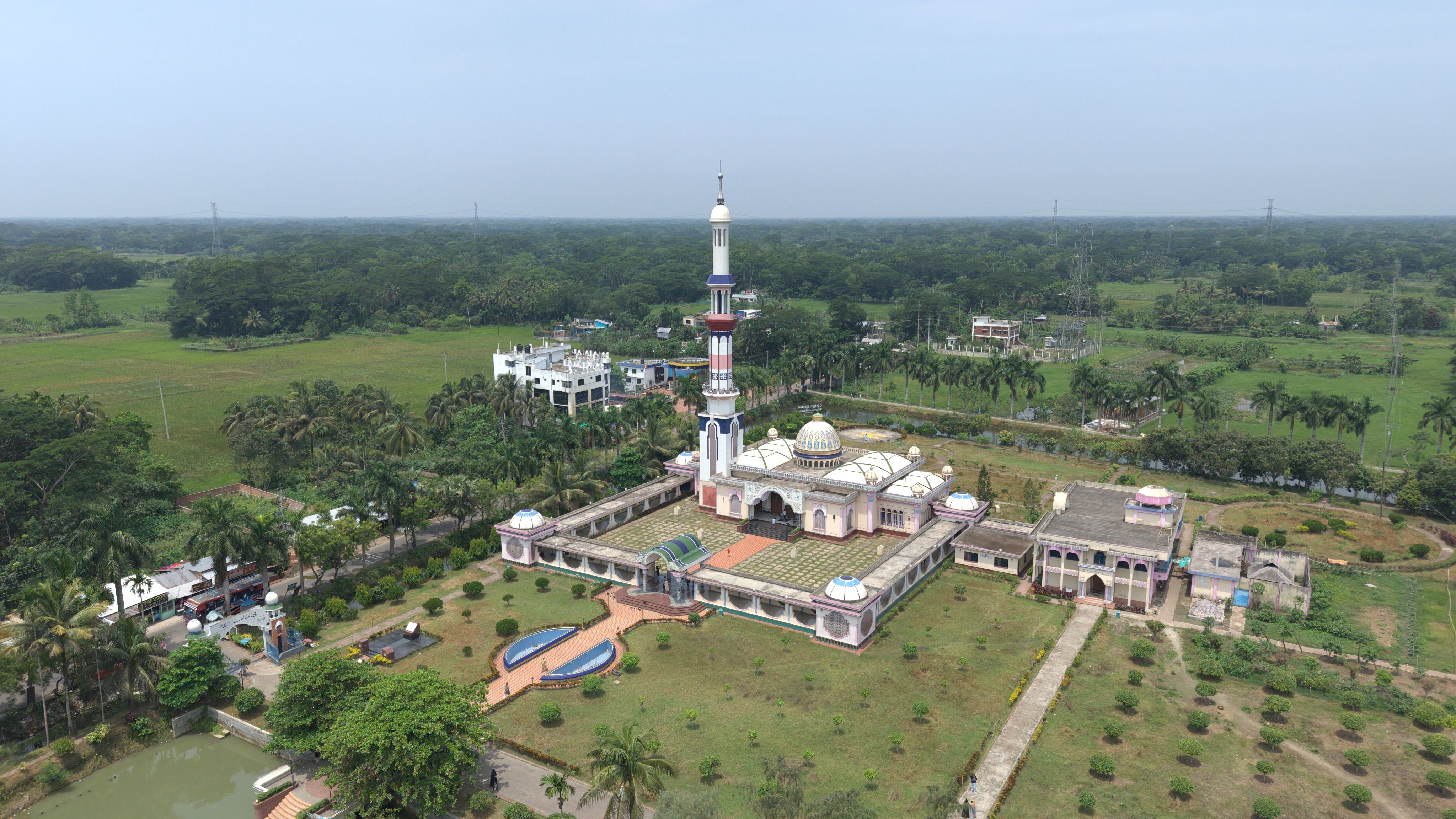A stunning aerial view of a mosque surrounded by lush greenery on a clear day.