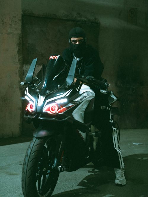 Free A motorcyclist with a mask on a sports bike in an urban night scene, suggesting mystery or adventure. Stock Photo
