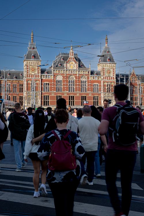 Free People crossing a street near the iconic Amsterdam Central Station in daylight. Stock Photo