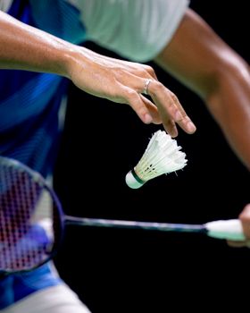 Close-up of a badminton player in action, focusing on handling a shuttlecock.