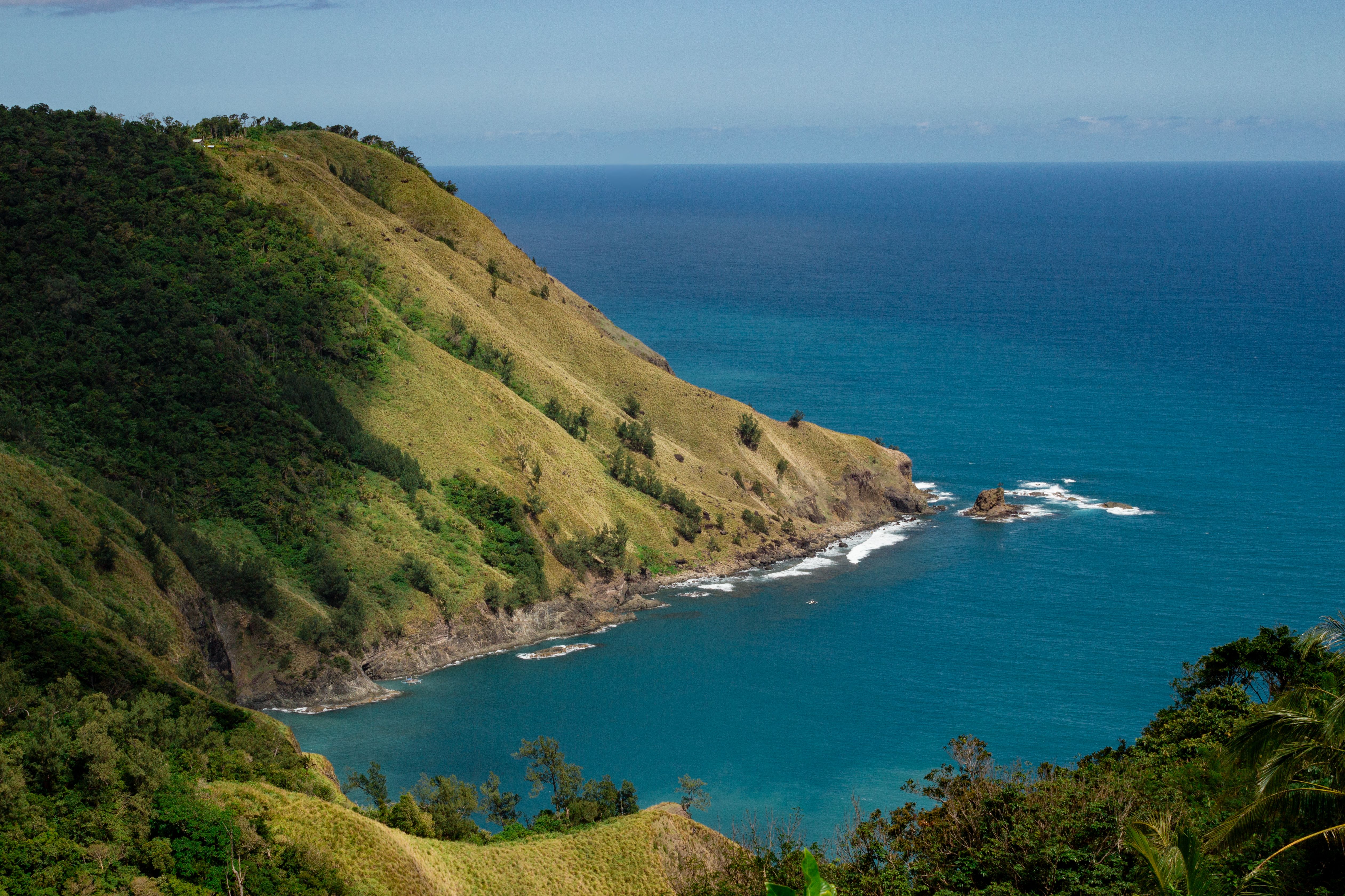 A stunning view of rugged green hills meeting the vibrant blue ocean.
