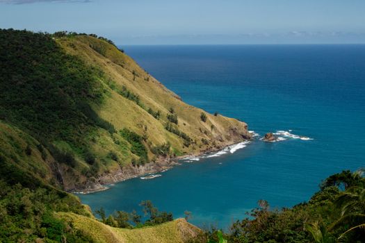 A stunning view of rugged green hills meeting the vibrant blue ocean.