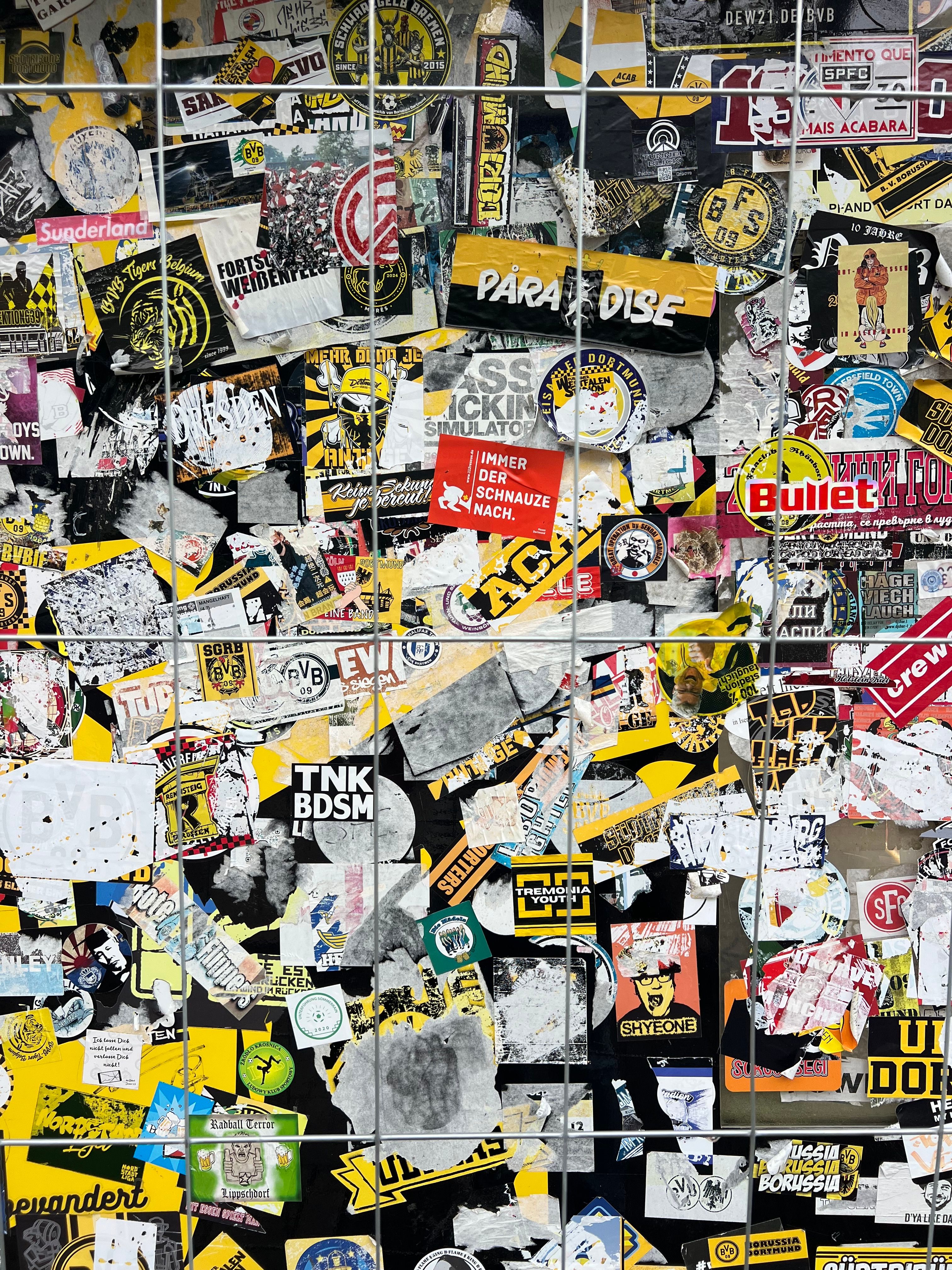 Vibrant collection of urban stickers covering a wall in Dortmund, Germany, showcasing artistic graffiti and diverse designs.