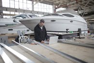 工程师在船舶车间里使用笔记本电脑，周围环绕着工具和游艇