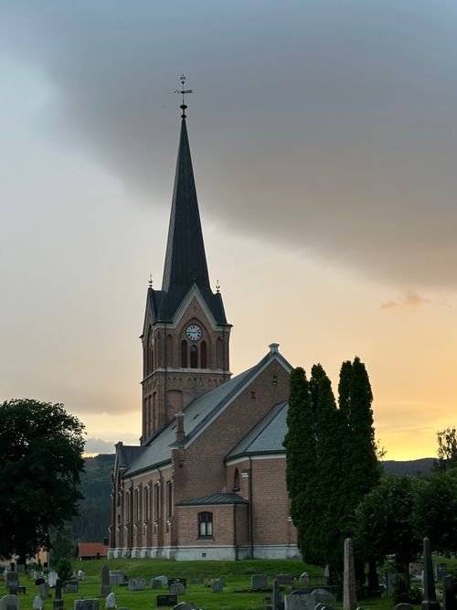 Free A stunning church with a tall spire stands against a sunset sky in Lillehammer, Norway. Stock Photo