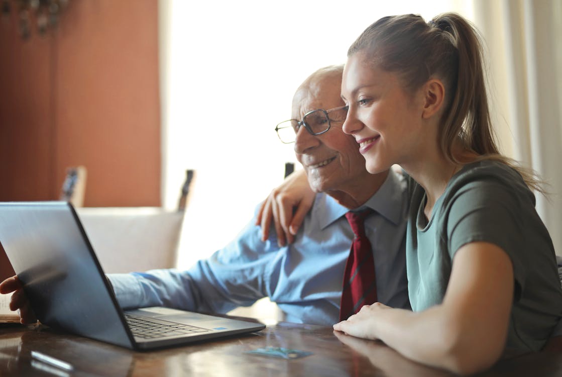 Free Young positive woman helping senior man using laptop Stock Photo