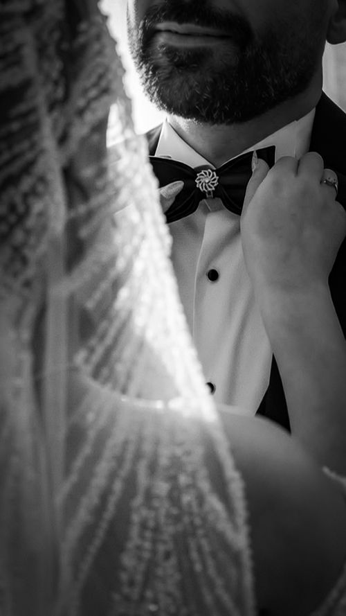 Free A close-up black and white shot of a bride adjusting a groom’s bow tie. Stock Photo