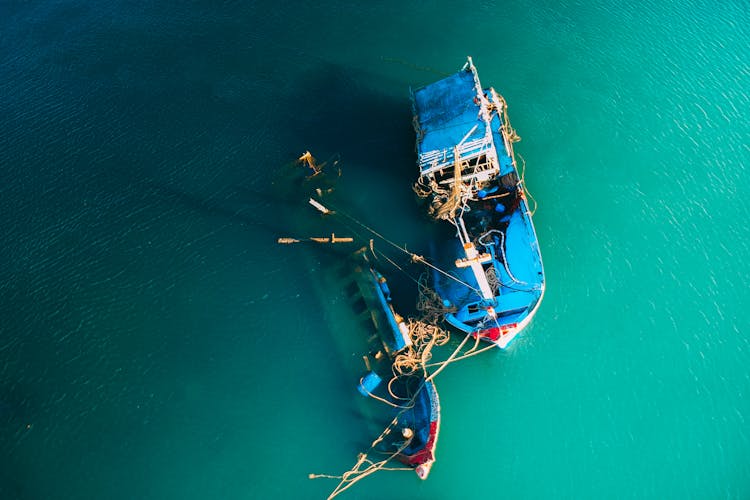 Half Sunken Boats In Sea With Colorful Water