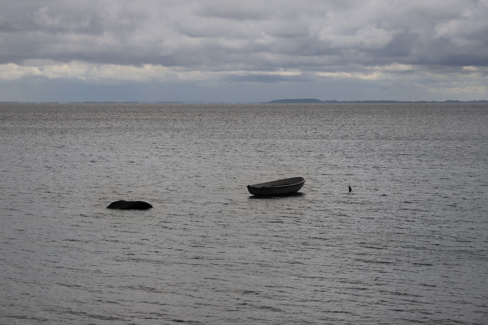 An empty fishing boat alone on a grey sea
