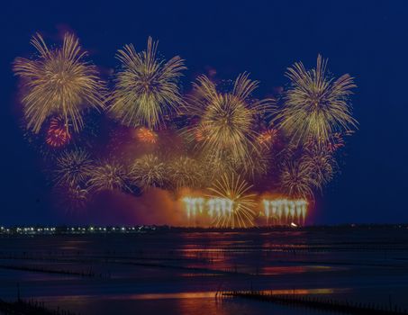 Vibrant fireworks exploding in the night sky reflected on water, creating a dazzling display.