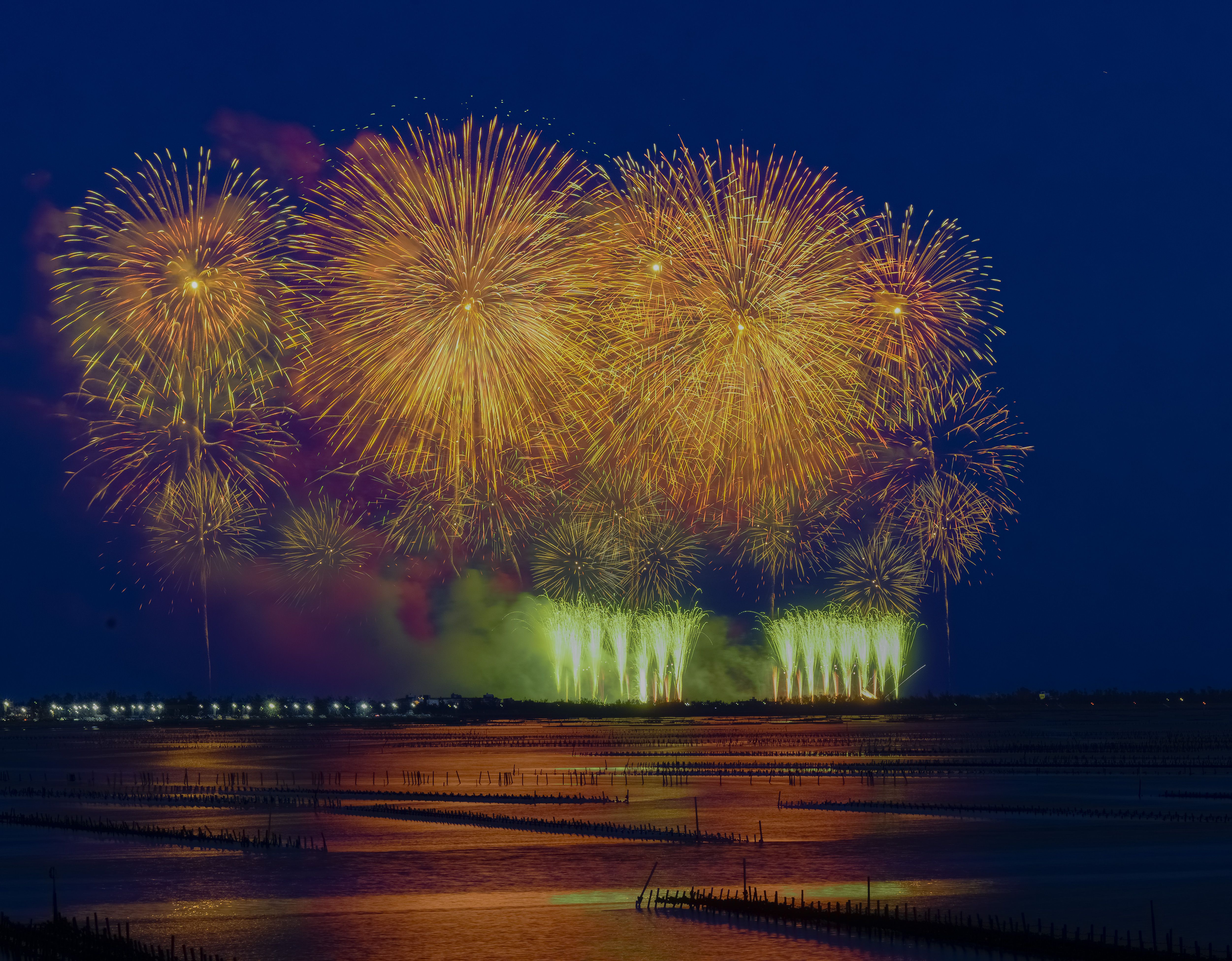 鮮やかな花火が静かな水面の上空を照らし、息を呑むような光景を創り出す。