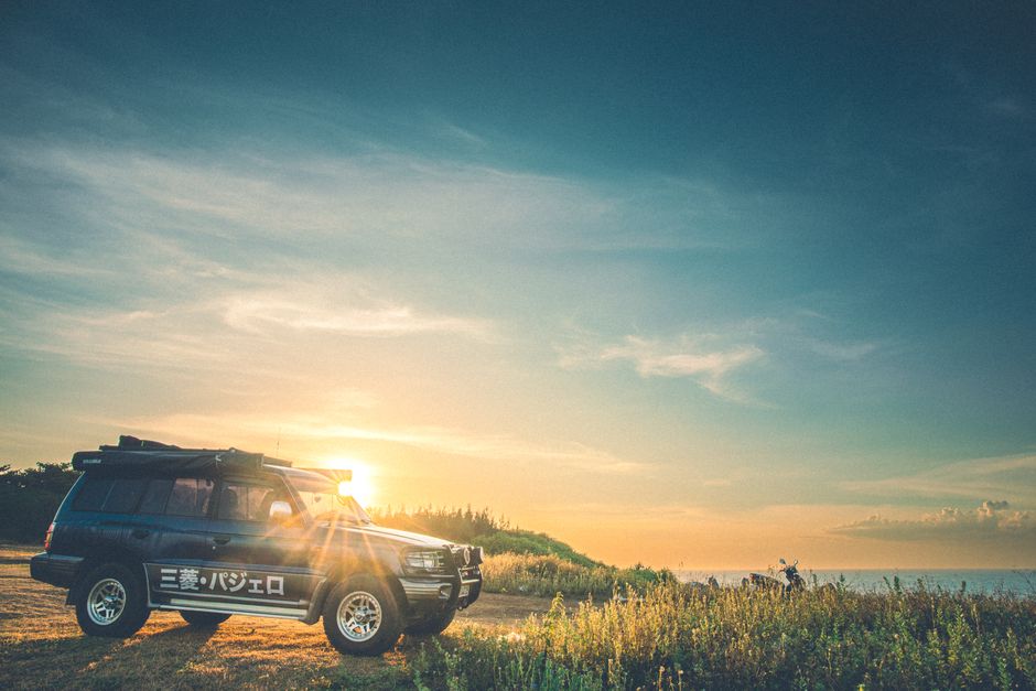 ベトナムのクアトゥンでの鮮やかなサンセット中に海のそばに駐車した頑丈なSUV。