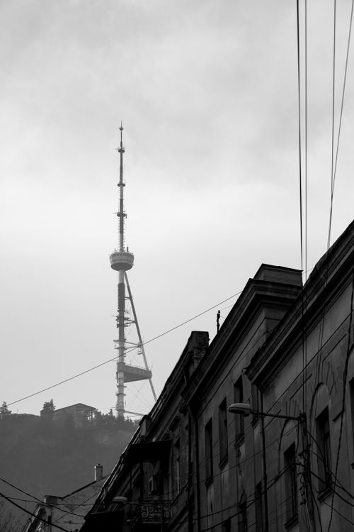 Free Monochrome silhouette of a TV tower rising above urban rooftops and cables. Stock Photo
