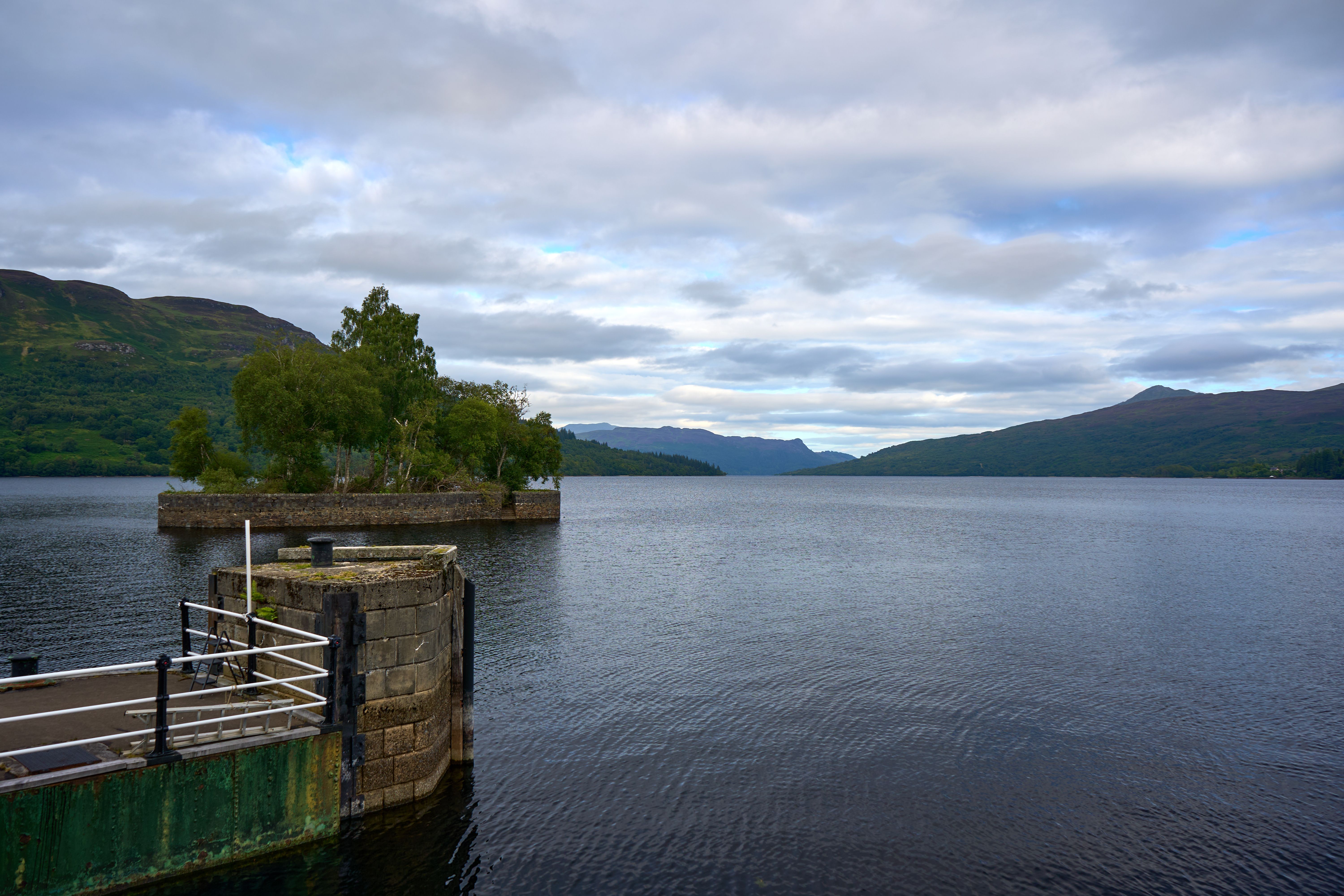 Serene landscape of Loch Katrine with lush greenery and mountains, Trossachs, Scotland.
