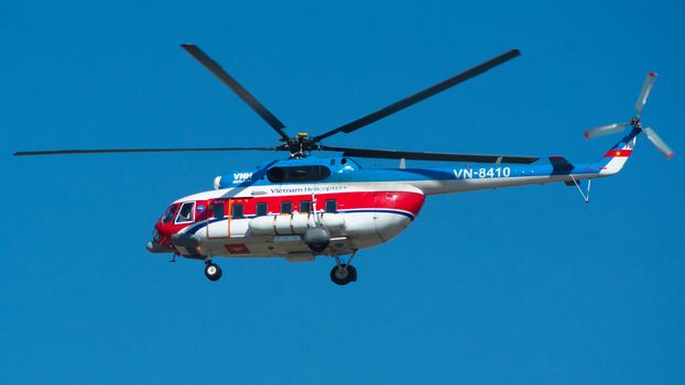 A colorful Mil Mi-8 helicopter flies against a clear blue sky, showcasing its vibrant design.