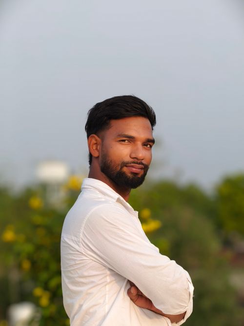 Free Portrait of a confident man in a white shirt standing outdoors with a blurred natural background. Stock Photo