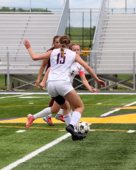 Young female soccer players competing in a lively match outdoors on a grass field.