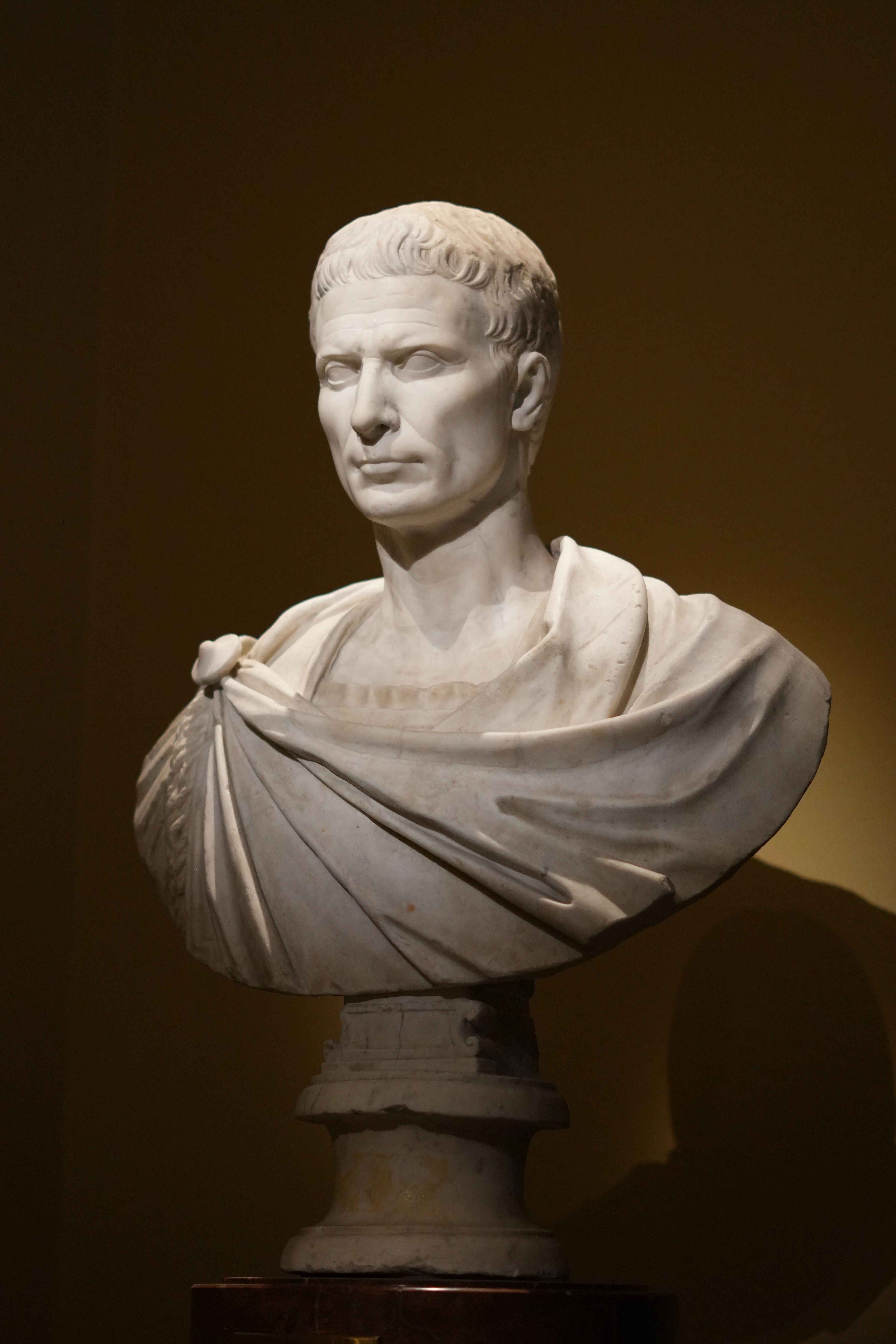 Elegant marble bust of a Roman figure displayed in a Vienna museum with dramatic lighting.