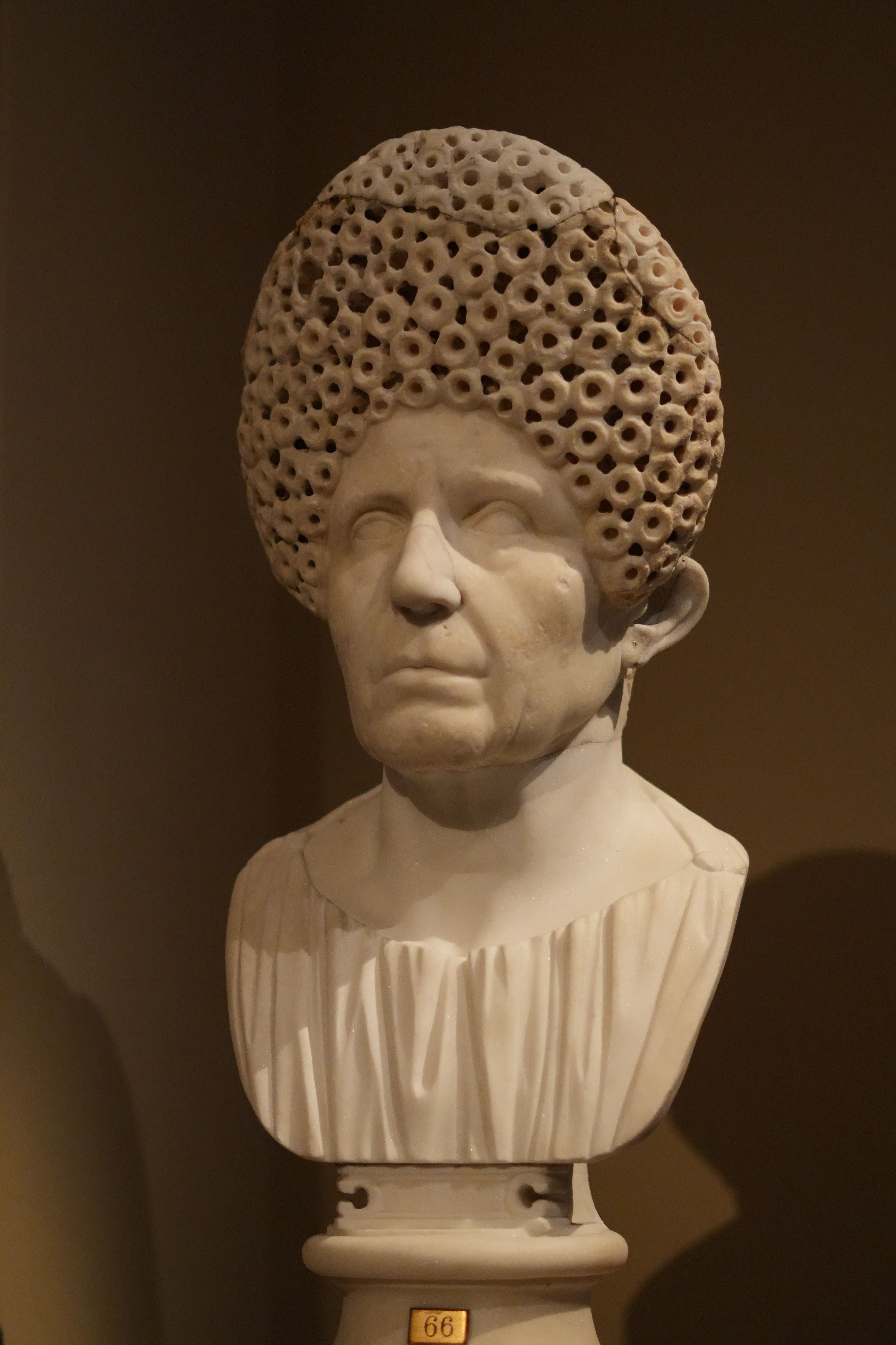 Marble bust of an ancient Roman woman with a detailed braided hairstyle, typical of Roman portrait art.