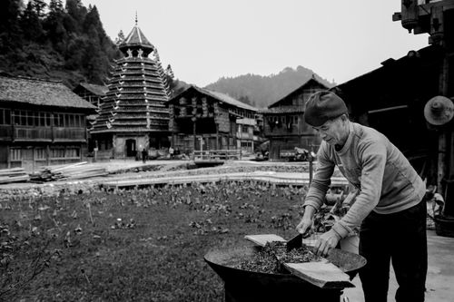 Free Black and white image of a man working outdoors in traditional Dong village in Qiandongnan, Guizhou, China. Stock Photo