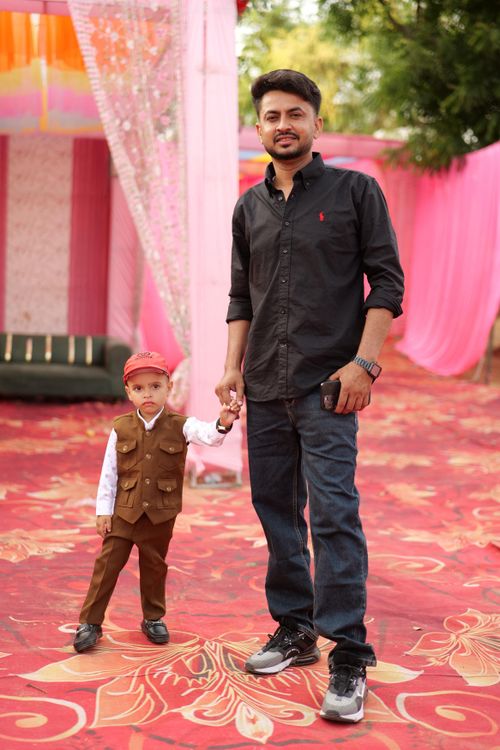Free Father and young son sharing a moment at a colorful outdoor celebration in Didwana, India. Stock Photo