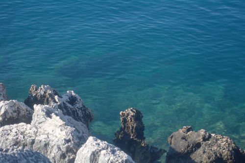 Free Serene image of clear blue waters near a rocky coastline, evoking a sense of peace and nature. Stock Photo