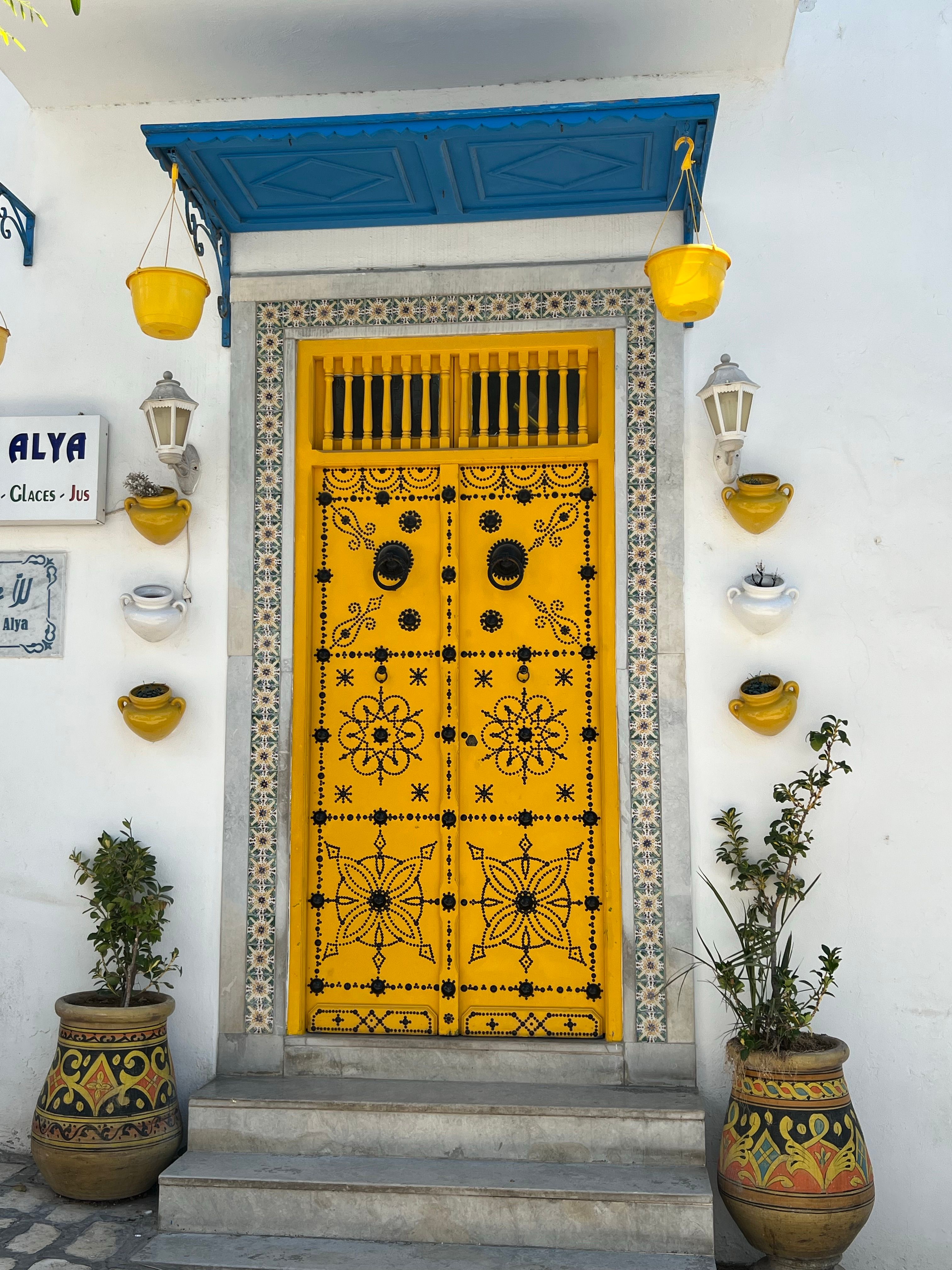 Vibrant yellow and blue Tunisian doorway with decorative elements and pottery.