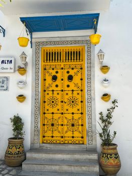 Vibrant yellow and blue Tunisian doorway with decorative elements and pottery.