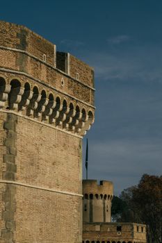View of Castel Sant'Angelo's ancient brickwork and towers under a clear sky.