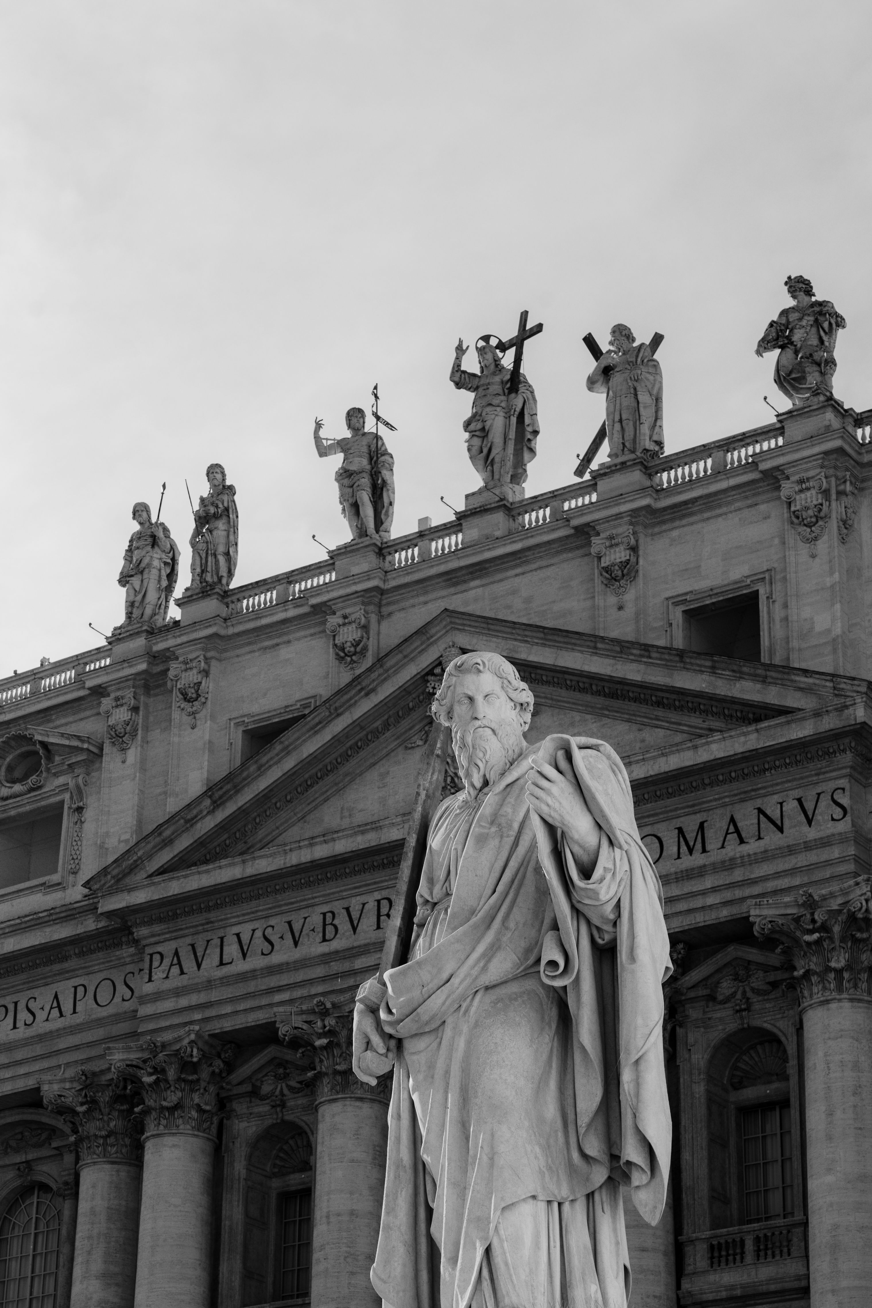 Dramatic black and white image of St. Peter's Basilica statues in Rome, highlighting classical architecture.