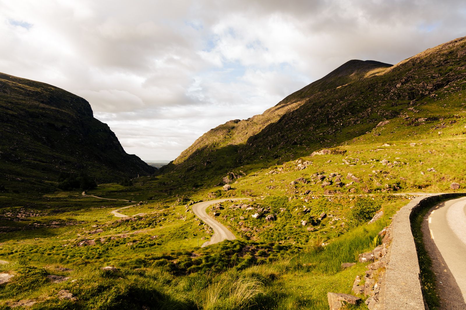 Winding road through green hills in County Kerry, Ireland, under a bright sky