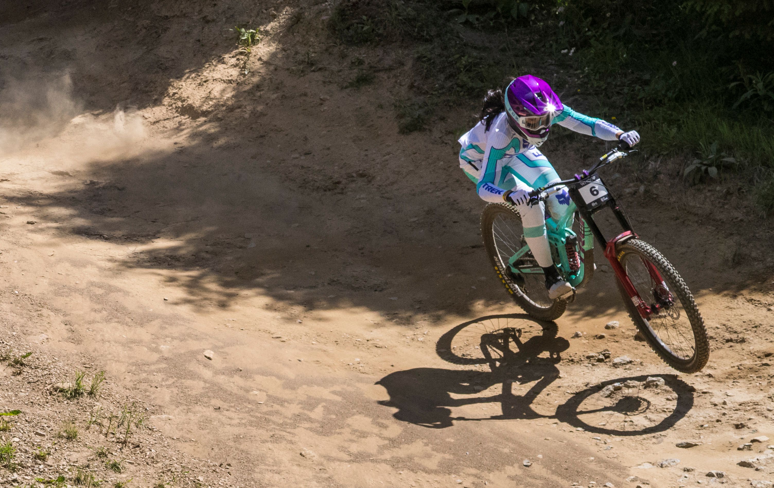A biker in vibrant gear navigates a dirt track during a sunny day in Vaz, Switzerland.