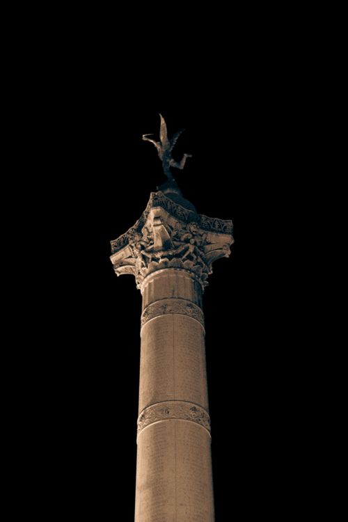 Free A majestic historic column with a statue on top, set against a dark night sky. Stock Photo