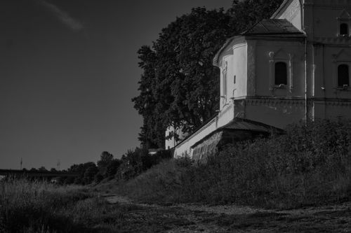 Free A serene black and white photo of a historic building surrounded by trees on a quiet path. Stock Photo