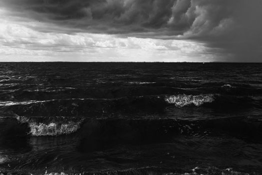 Captivating view of a turbulent ocean beneath dramatic storm clouds, captured in monochrome.