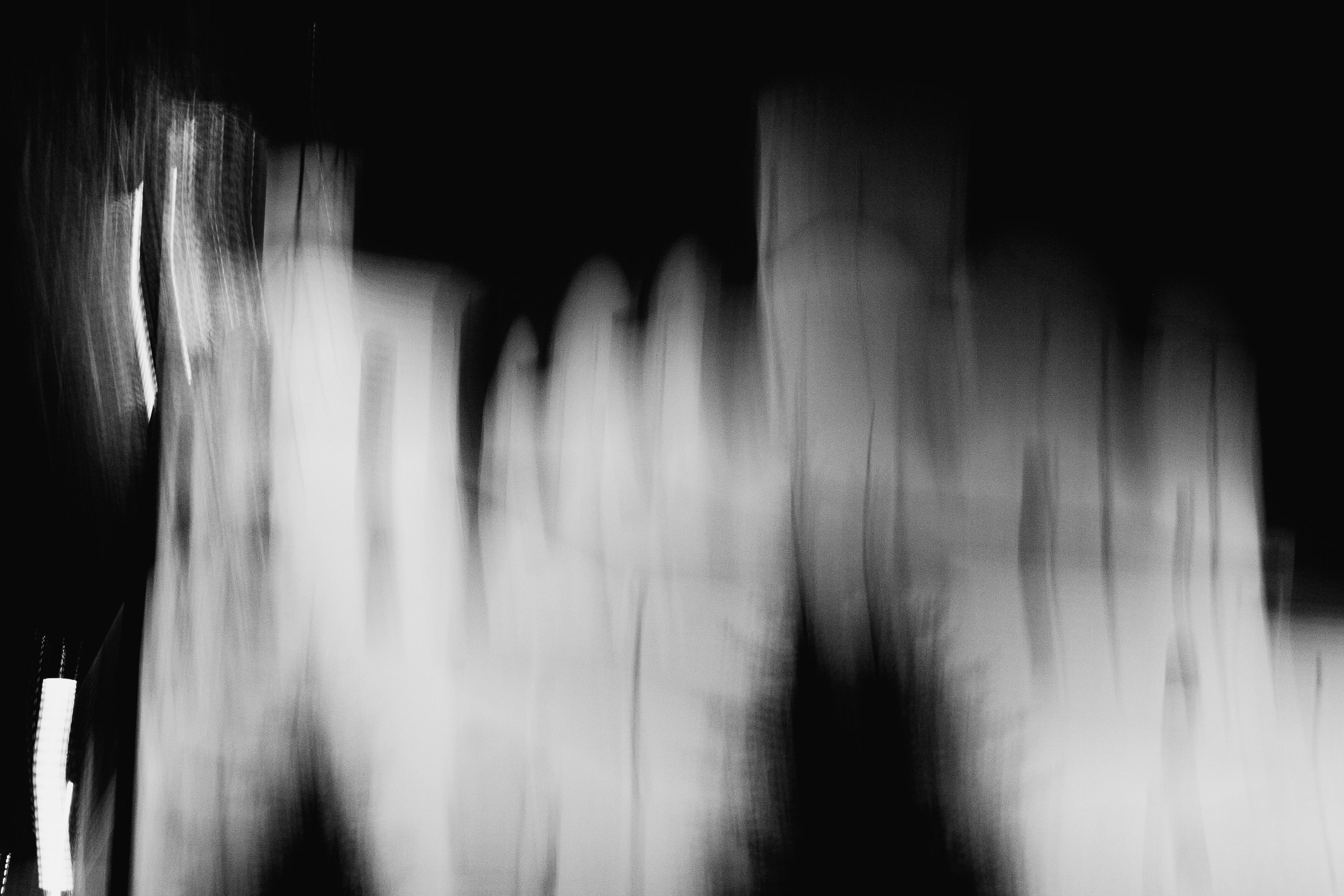 Black and white abstract image with blurred light streaks creating a dynamic effect.
