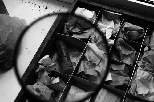 Free A vintage collection box filled with various papers, viewed through a magnifying glass. Stock Photo