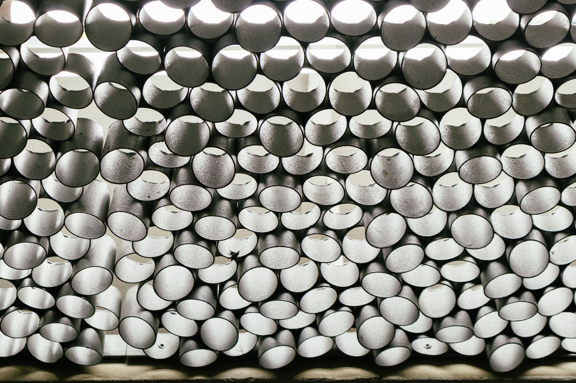 Artistic arrangement of metallic pipes creating a unique abstract pattern viewed from below.