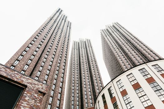 Low angle view of modern high-rise buildings with visible facade details against a bright sky.